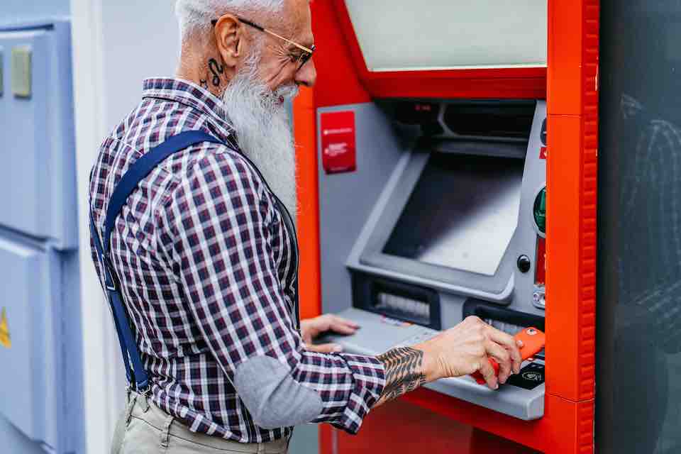 A man using contactless payment technology to withdraw from an ATM.