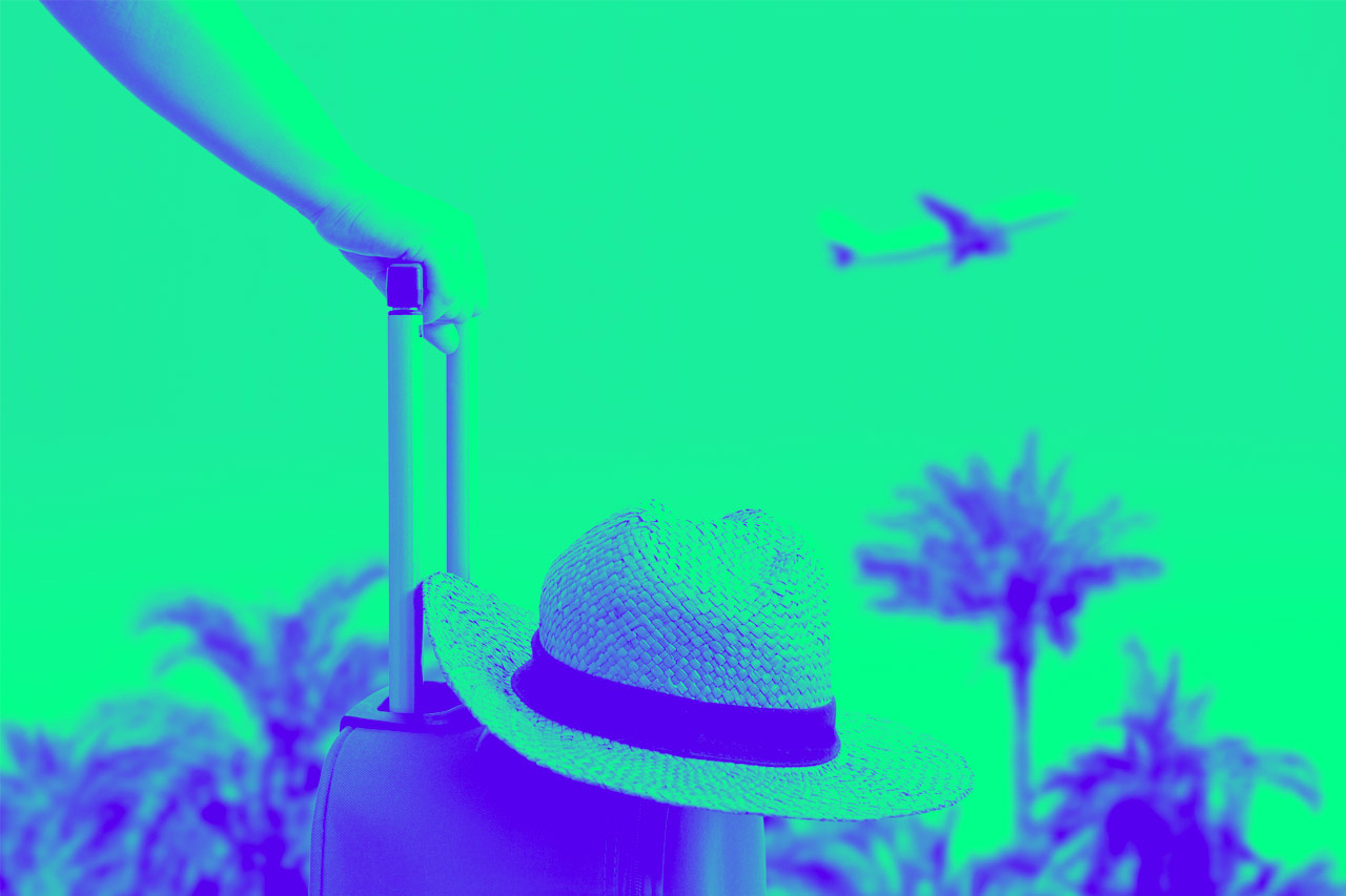 A woman is holding a suitcase and a hat on it with an airplane in the background